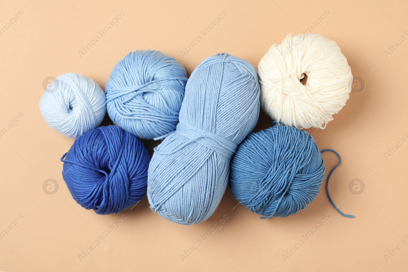 Photo of Soft woolen yarns on beige background, flat lay