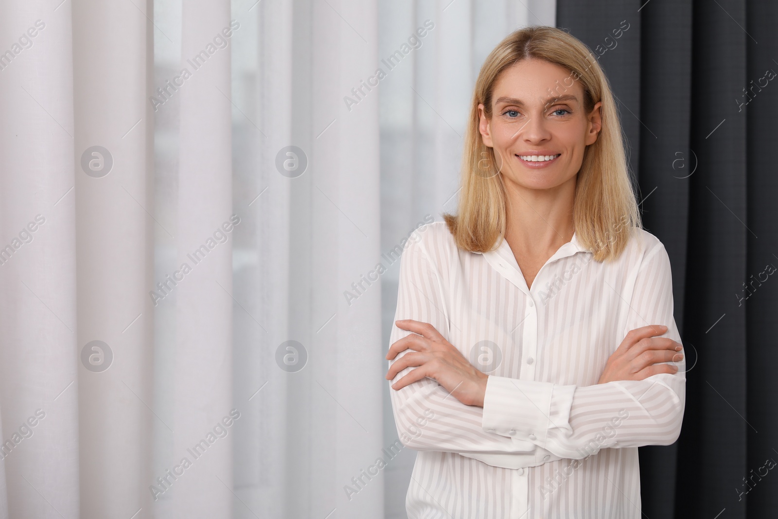Photo of Portrait of confident entrepreneur or businesswoman with crossed arms, space for text. Beautiful lady with blonde hair smiling and looking into camera
