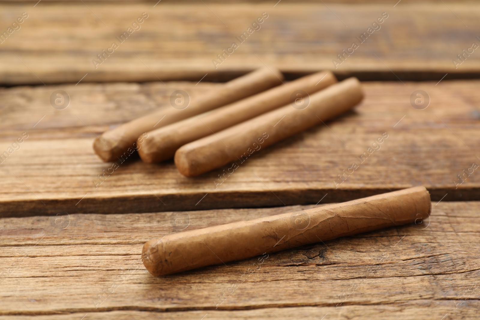 Photo of Many cigars on wooden table. Tobacco smoking