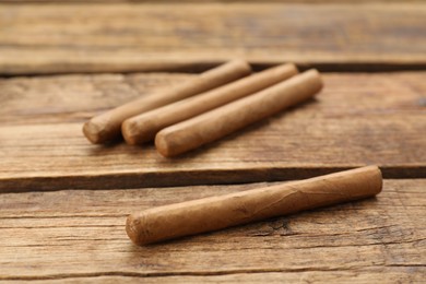 Photo of Many cigars on wooden table. Tobacco smoking