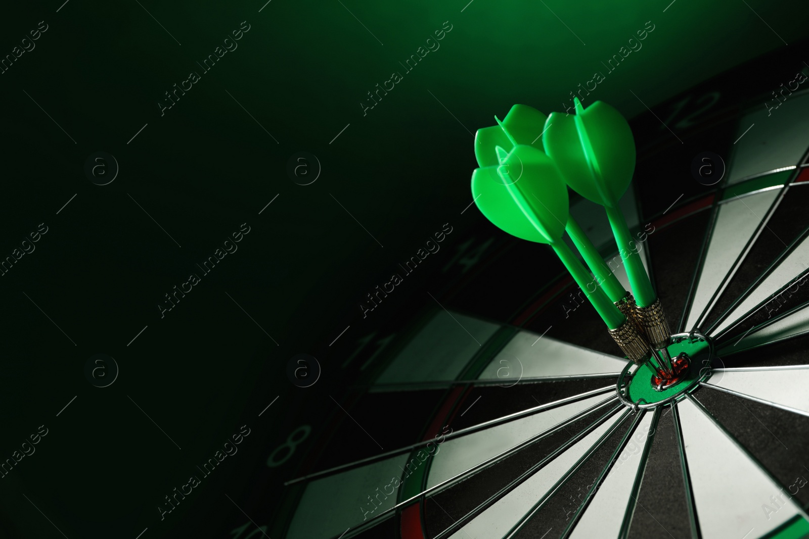 Photo of Color arrows hitting target on dart board against green background. Space for text