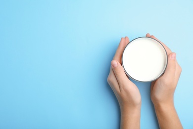 Woman holding glass of milk on color background, top view. Space for text