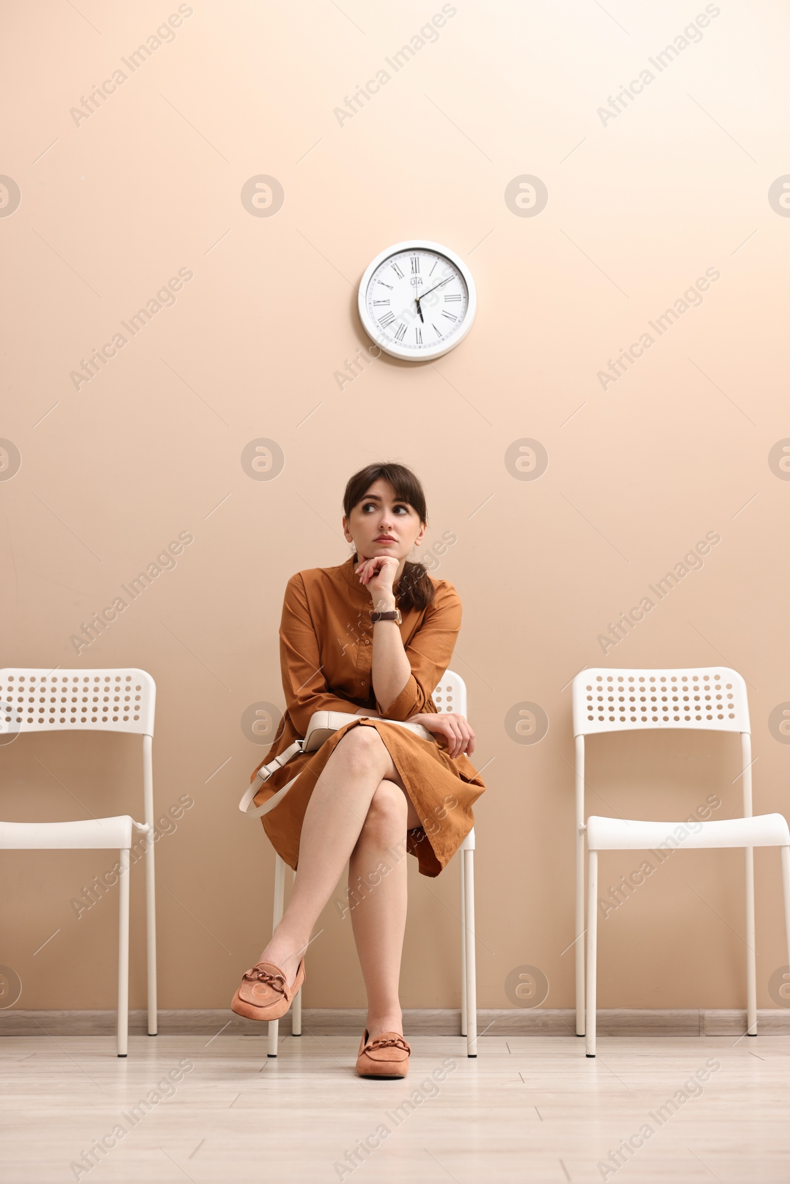 Photo of Woman sitting on chair and waiting for appointment indoors