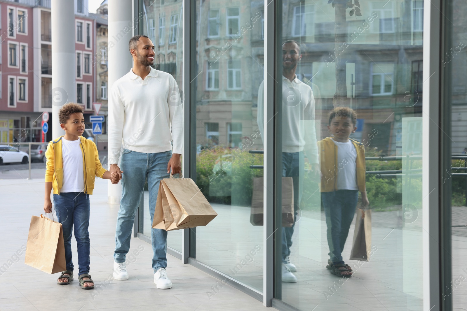 Photo of Family shopping. Happy father and son with purchases near mall outdoors