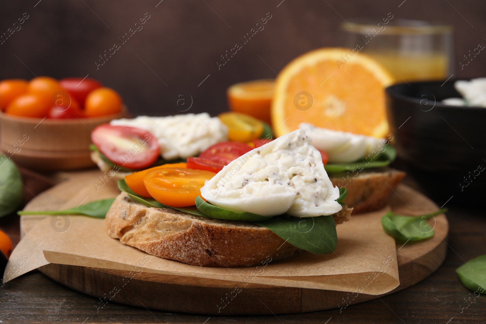 Photo of Delicious sandwich with burrata cheese and tomatoes on wooden table, closeup