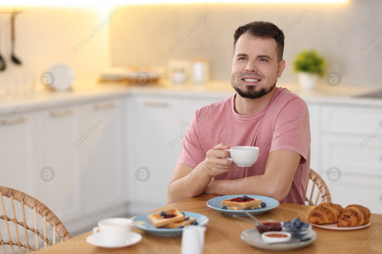 Photo of Smiling man drinking coffee at breakfast indoors. Space for text