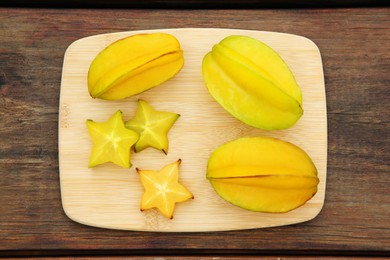 Cut and whole delicious ripe carambolas on wooden table, top view