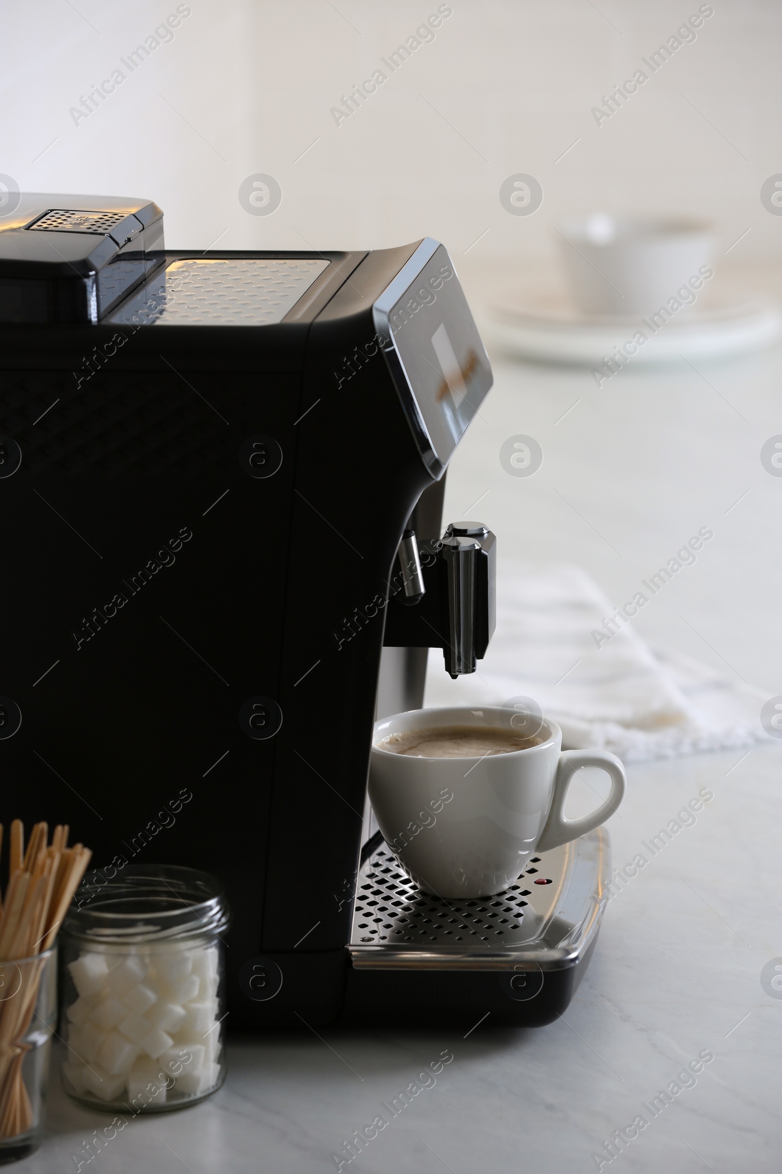 Photo of Modern electric espresso machine with cup of coffee on white marble countertop in kitchen