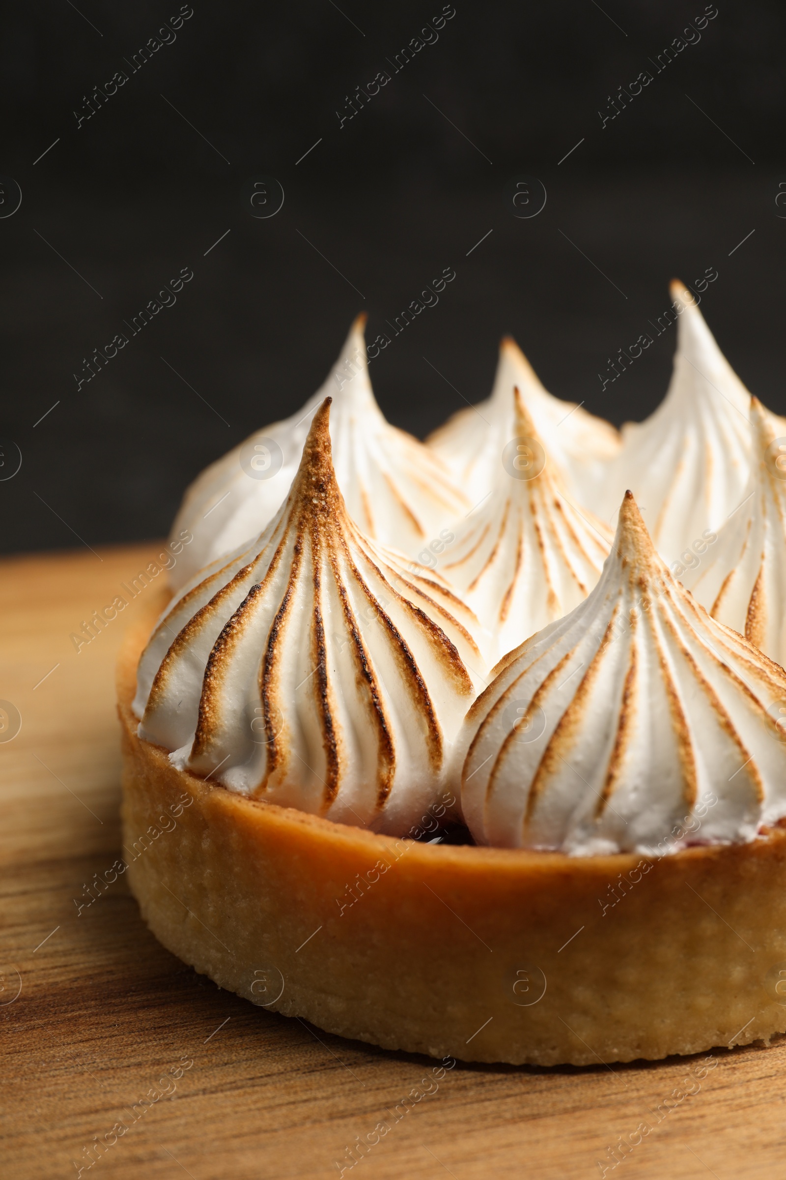 Photo of Tartlet with meringue on wooden board, closeup. Delicious dessert