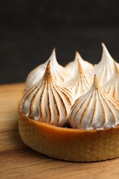 Photo of Tartlet with meringue on wooden board, closeup. Delicious dessert