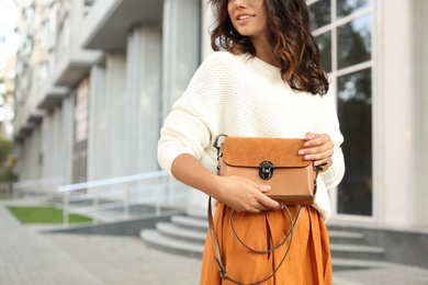 Photo of Young woman with stylish brown bag on city street, closeup