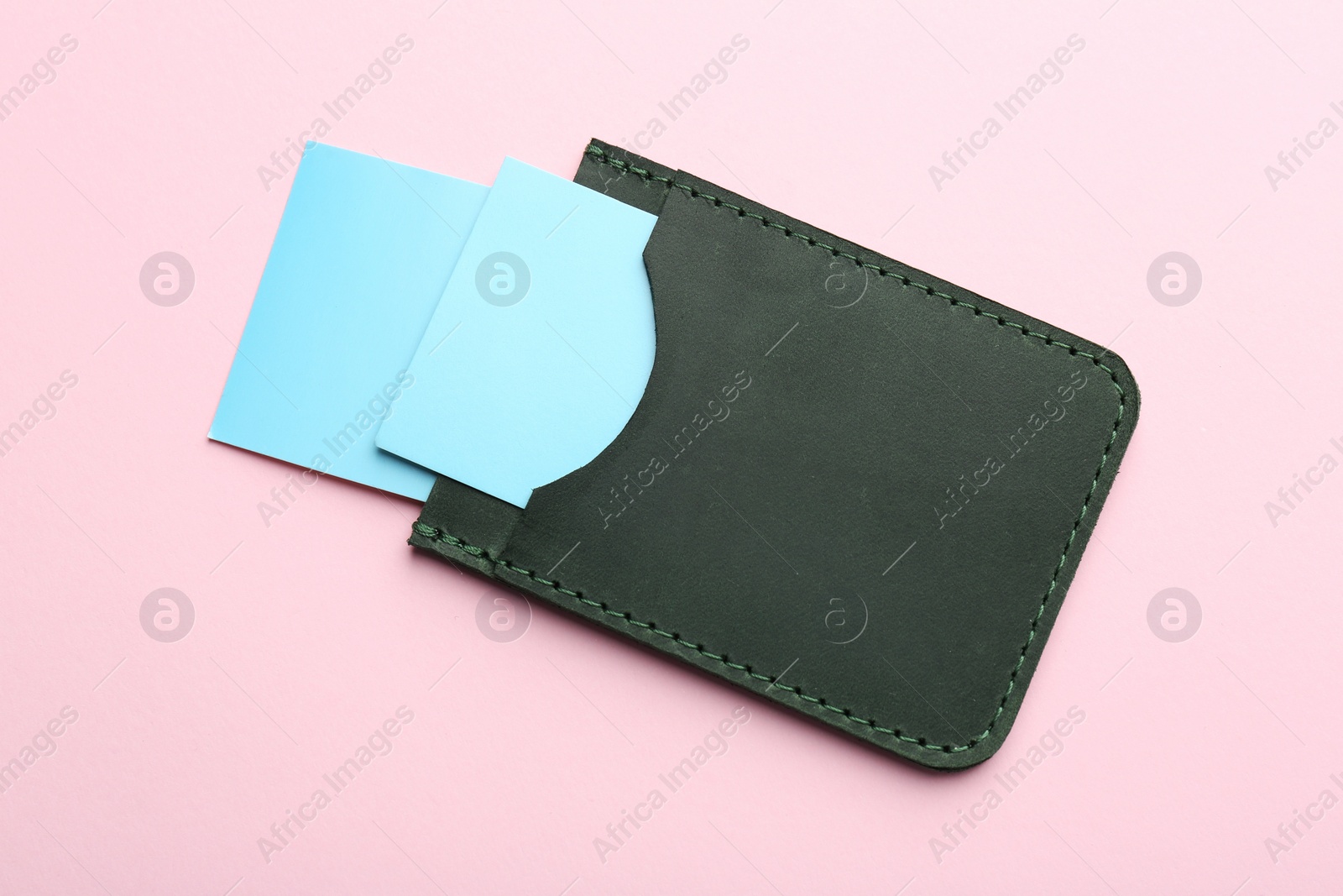 Photo of Leather business card holder with blank cards on pink background, top view