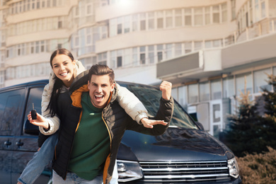 Happy couple with key near car on city street. Buying new auto