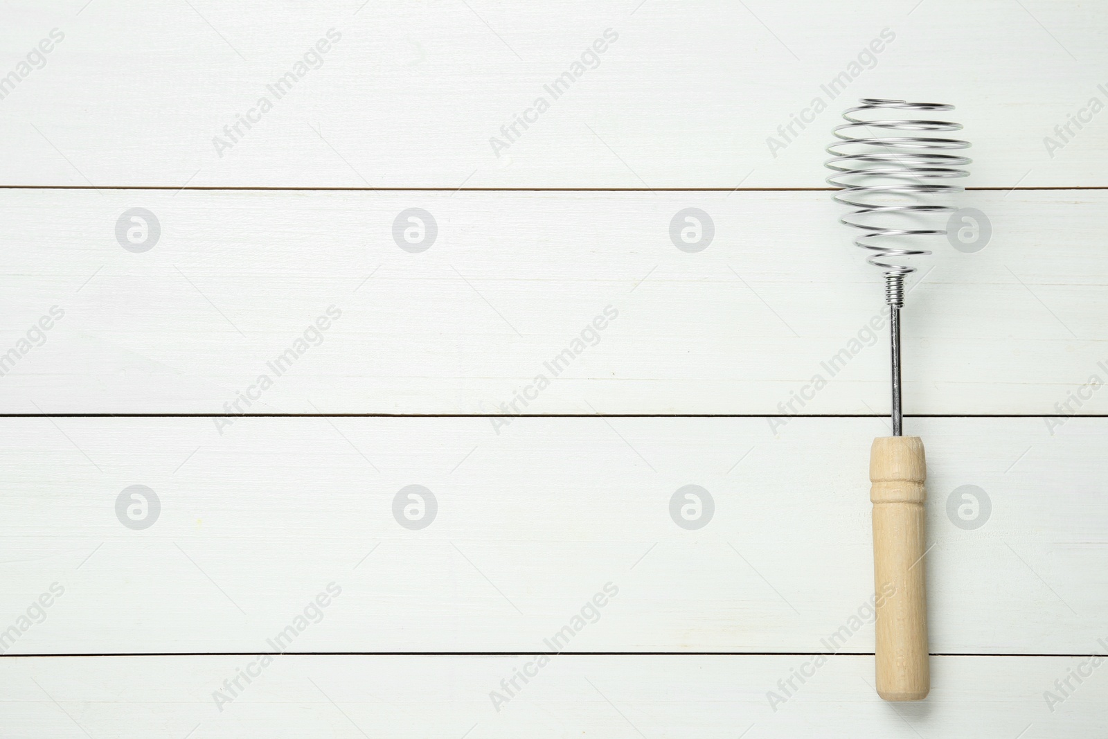 Photo of Metal spring whisk on white wooden table, top view