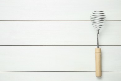 Photo of Metal spring whisk on white wooden table, top view
