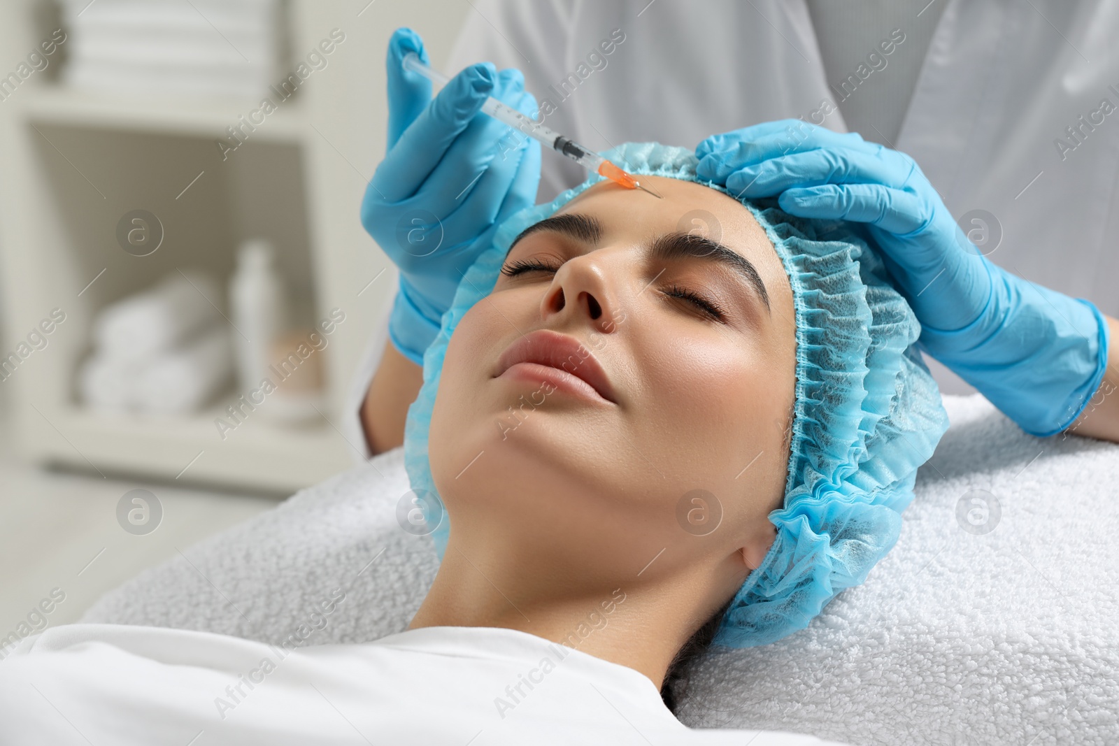 Photo of Doctor giving facial injection to young woman in clinic. Cosmetic surgery