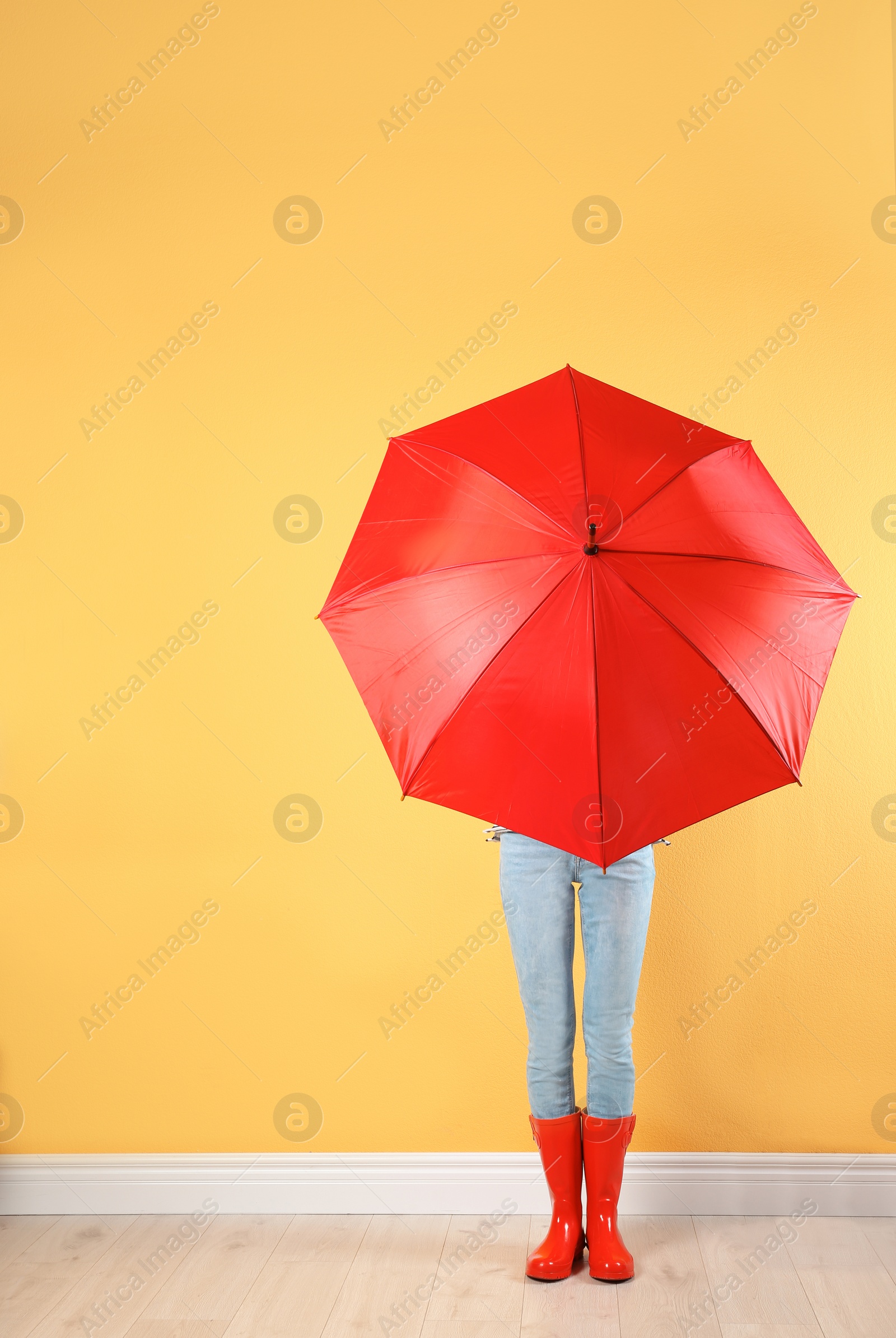 Photo of Woman hiding behind red umbrella near color wall