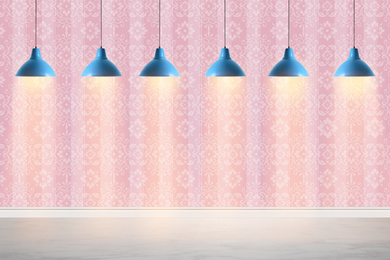 Pink patterned wallpaper and glowing hanging lamps in room