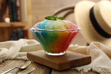 Photo of Rainbow shaving ice in glass dessert bowl on wooden  table indoors