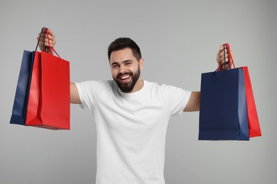 Photo of Happy man with many paper shopping bags on grey background