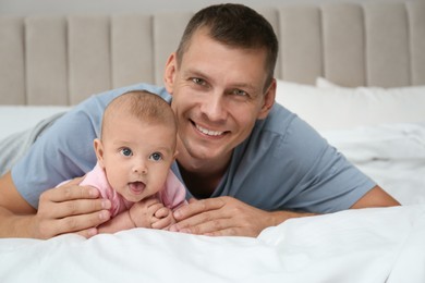 Photo of Happy father with his cute baby on bed at home