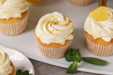 Delicious lemon cupcakes with white cream and mint on table, closeup