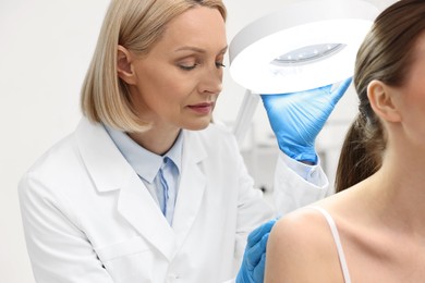 Photo of Dermatologist examining patient under lamp in clinic