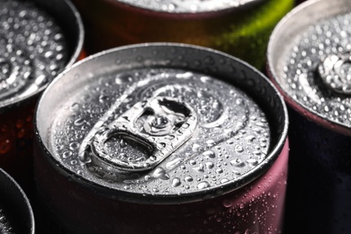 Aluminum cans of beverage covered with water drops as background, closeup