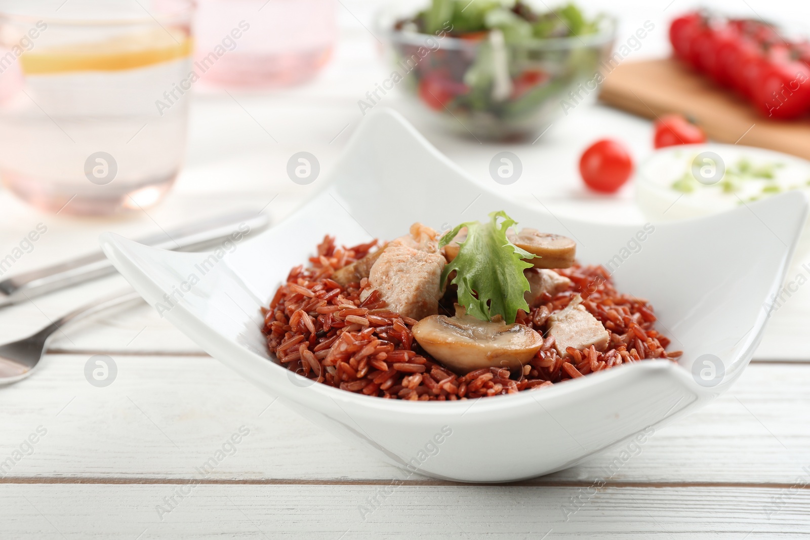 Photo of Tasty brown rice with meat and vegetables on white wooden table