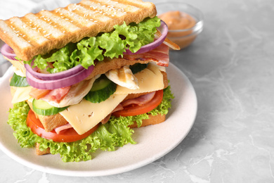 Photo of Tasty sandwich with chicken, ham and bacon on grey table, closeup
