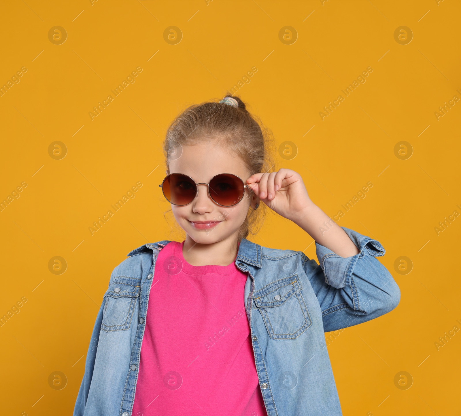 Photo of Girl in stylish sunglasses on orange background