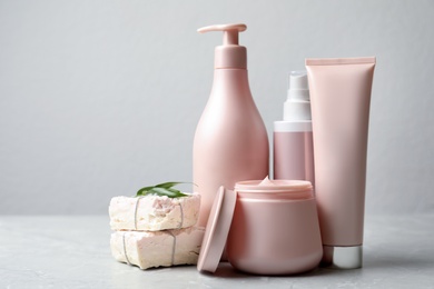 Photo of Set of hair care cosmetic products and soap bars on light grey marble table