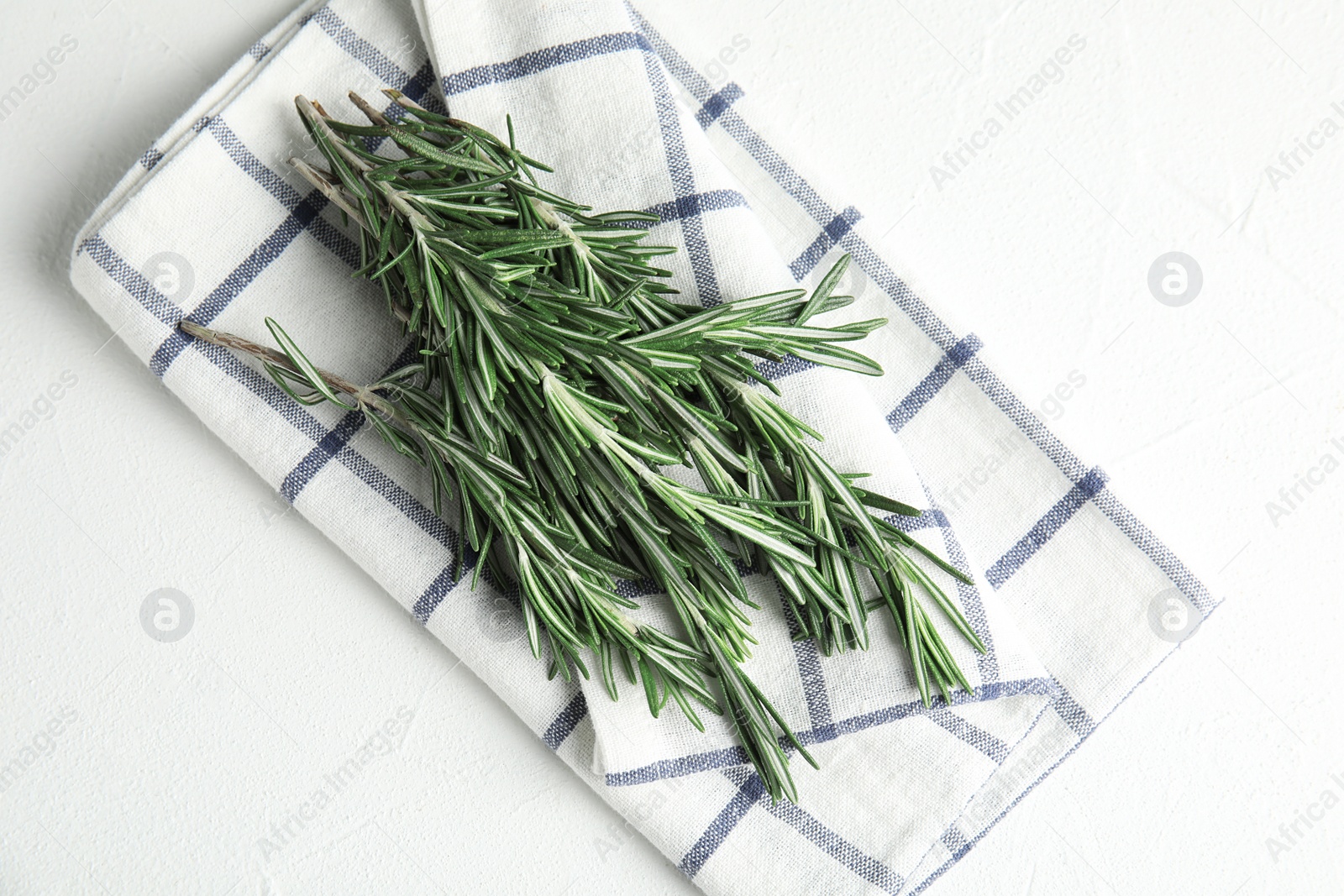 Photo of Fresh green rosemary and napkin on white table, top view