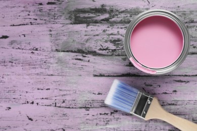 Photo of Can of pink paint and brush on rustic wooden table, flat lay. Space for text