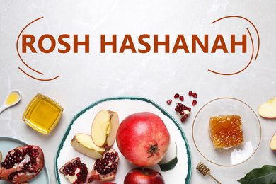 Honey, apples and pomegranates on white table, flat lay. Rosh Hashanah holiday