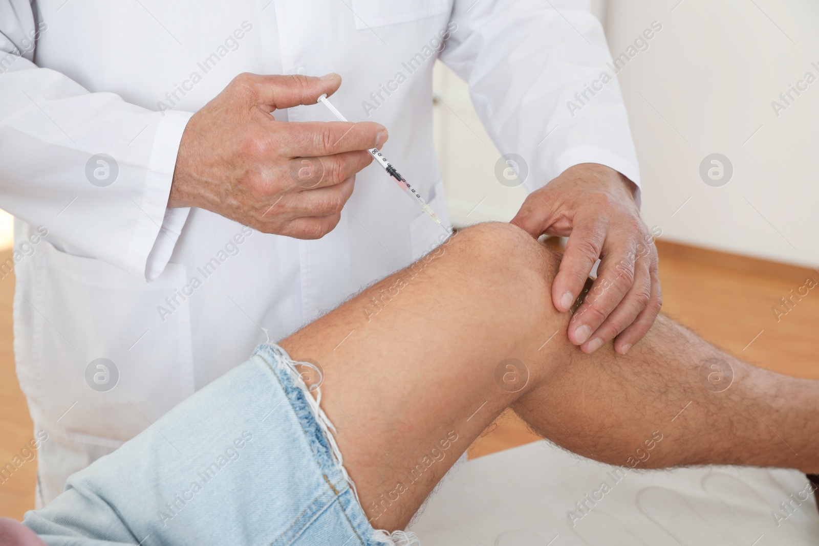 Photo of Doctor giving patient injection in clinic, closeup. Knee problem treatment