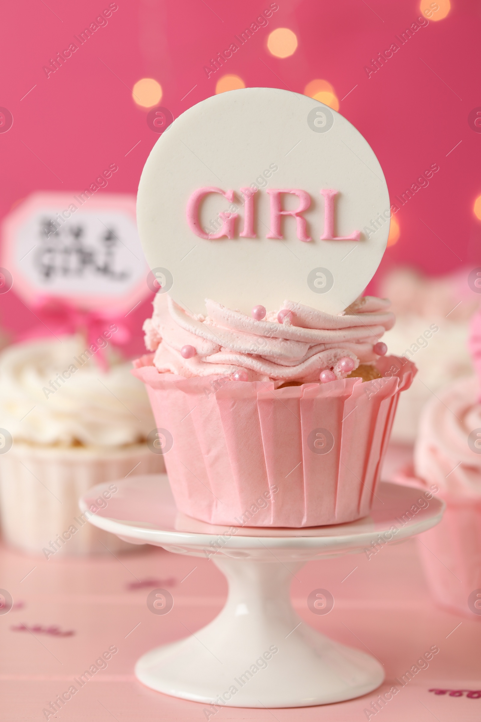 Photo of Beautifully decorated baby shower cupcake for girl with cream and topper on pink wooden table