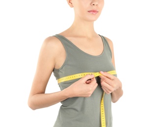 Photo of Young woman measuring breast size on white background, closeup. Cosmetic surgery