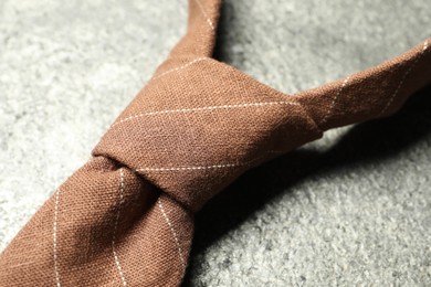 One striped necktie on grey textured background, closeup