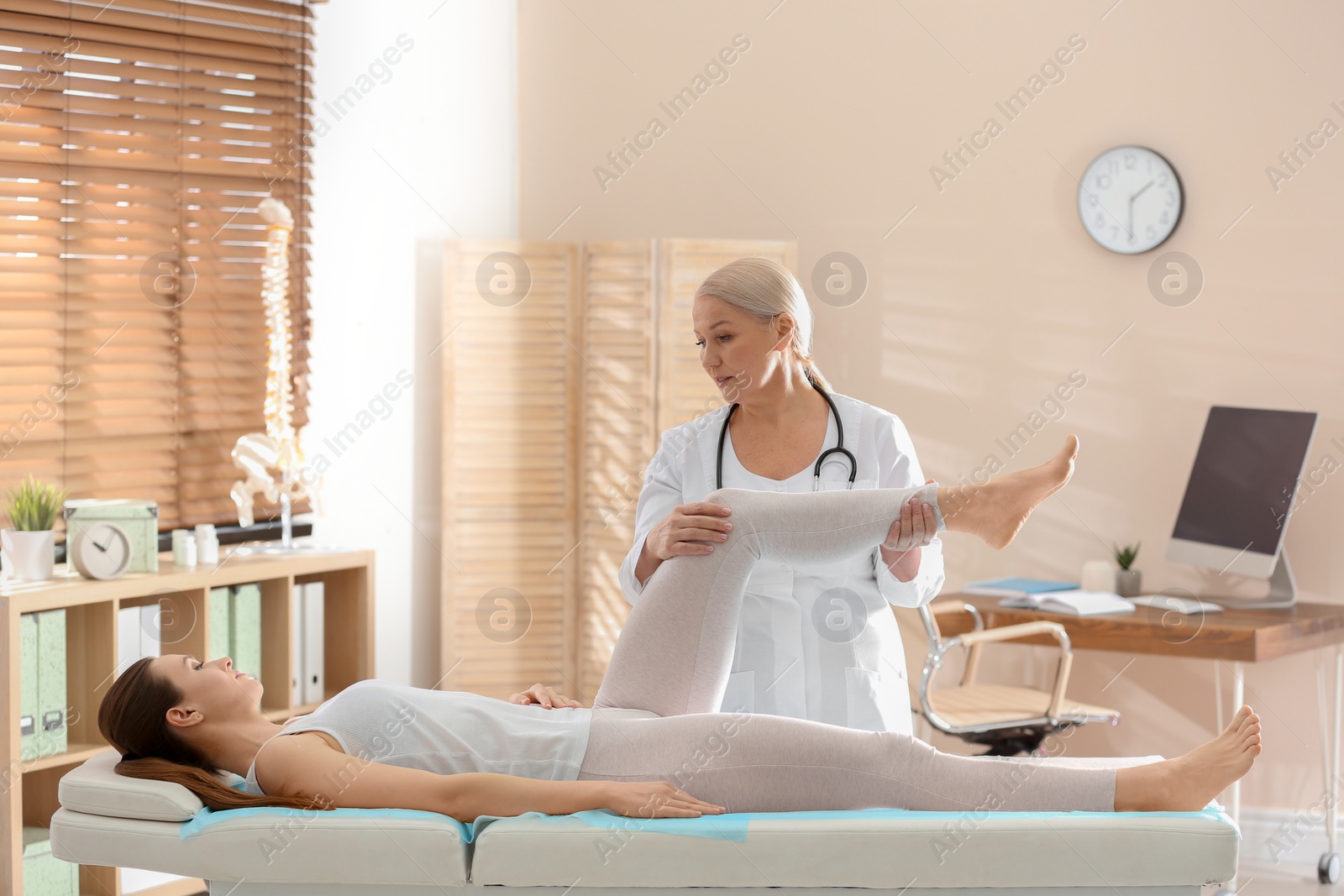 Photo of Female orthopedist examining patient's leg in clinic