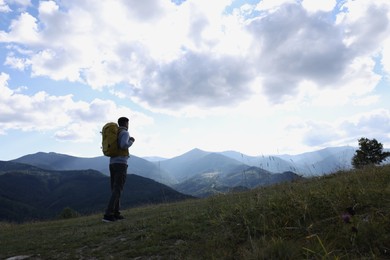 Photo of Tourist with backpack enjoying mountain landscape, space for text