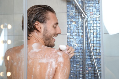 Photo of Young man taking shower with soap. Space for text