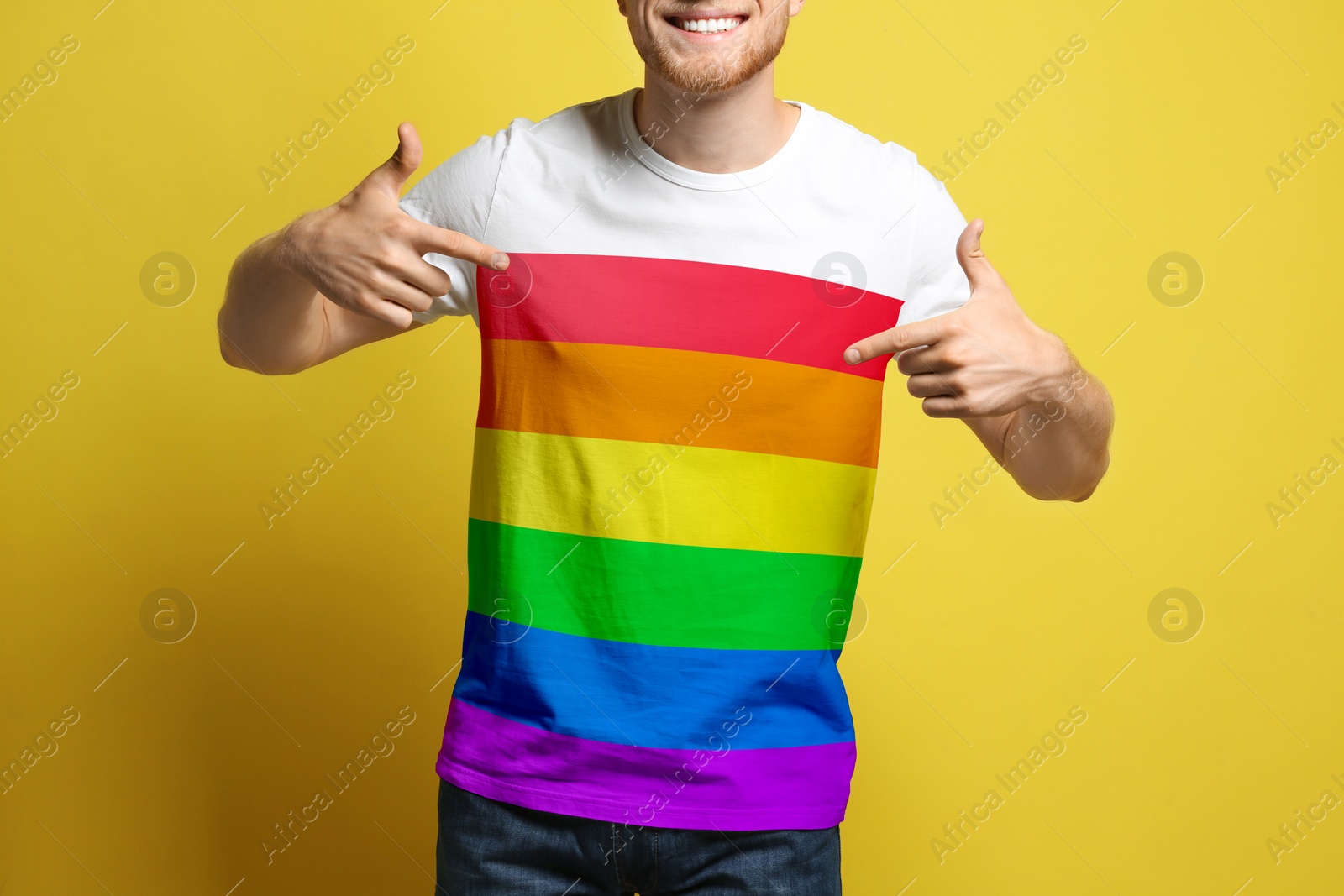 Image of Young man wearing t-shirt with image of LGBT pride flag on yellow background