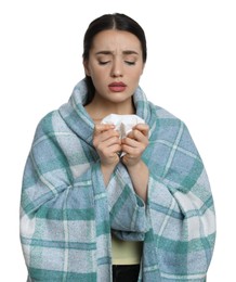 Young woman wrapped in blanket with tissue suffering from cold on white background