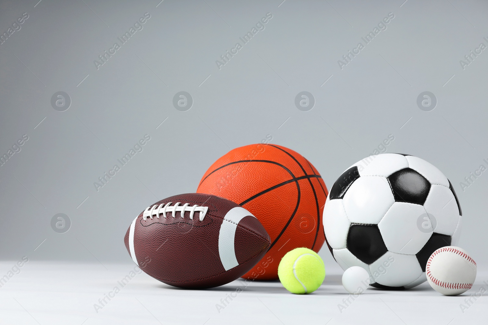 Photo of Many different sports balls on light gray background, space for text