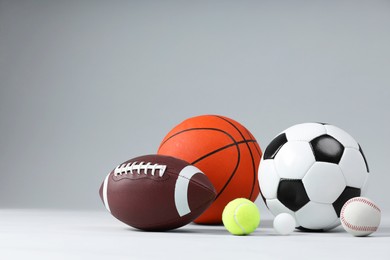 Photo of Many different sports balls on light gray background, space for text