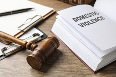 Photo of Wooden gavel and law book on wooden table. Protection from domestic violence