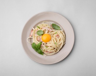 Photo of Delicious pasta Carbonara with egg yolk on light blue background, top view