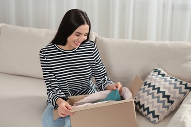 Photo of Happy woman unpacking parcel on sofa at home. Internet shopping