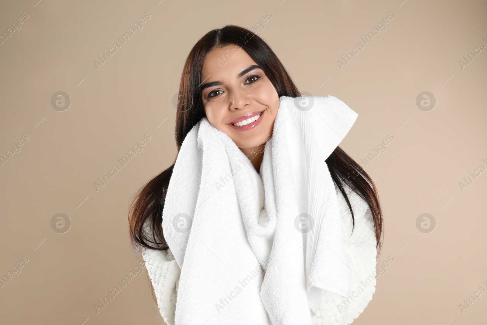 Photo of Young woman wiping face with towel on beige background